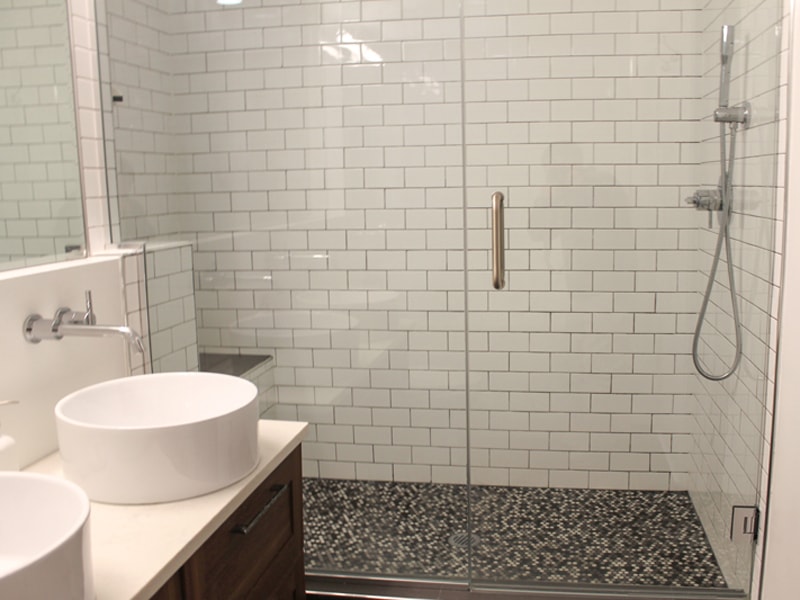 white subway tile shower with gray penny tile mosaic flooring