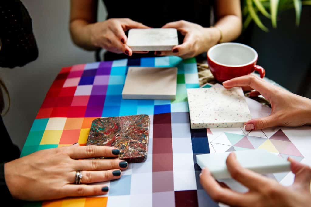 three women comparing several tile samples